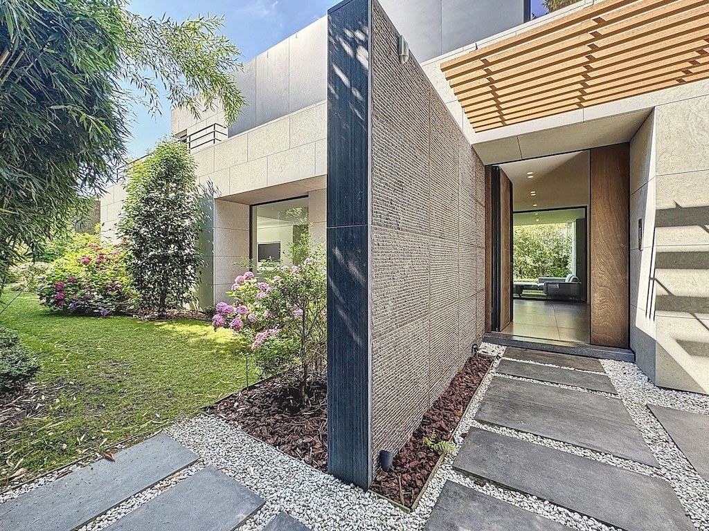 Entrée moderne avec jardin luxuriant, chemin en pierre et façade en pierre et bois élégante.