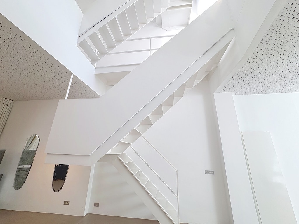 Escalier contemporain minimaliste en intérieur lumineux avec murs en miroir et design architectural épuré.