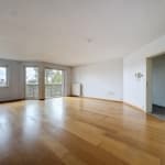 Espace lumineux et moderne avec sol en bois naturel et grandes fenêtres, idéal pour décoration minimaliste.