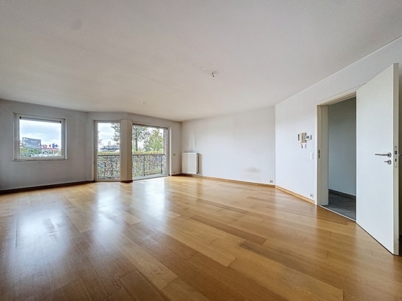 Espace lumineux et moderne avec sol en bois naturel et grandes fenêtres, idéal pour décoration minimaliste.