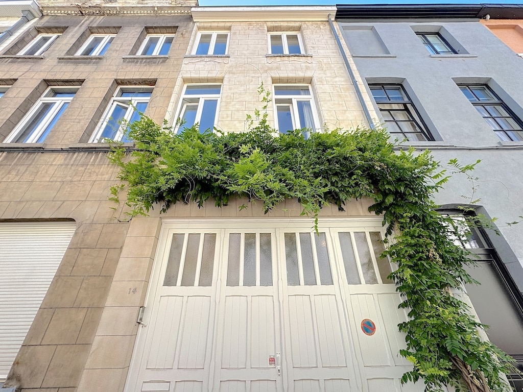 Façade urbaine avec végétation, styles variés, harmonie entre architecture et nature sous ciel bleu.