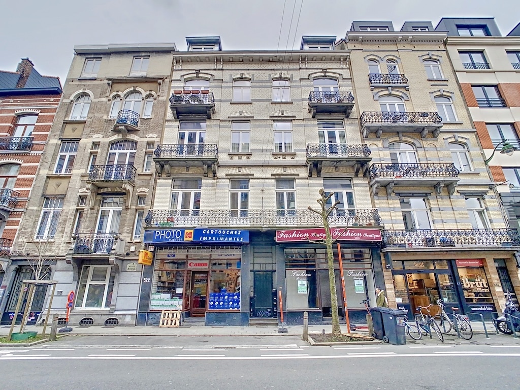 Quartier historique mêlant architecture classique, boutiques animées, vélos et bâtiments modernes sous ciel nuageux.
