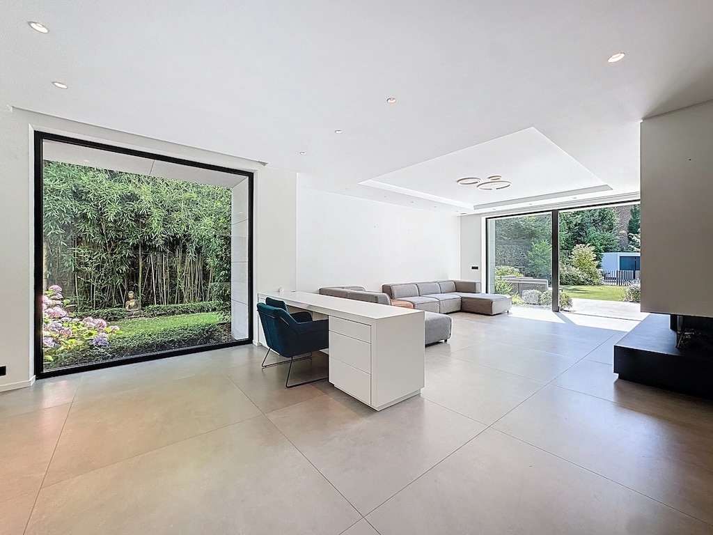 Salon moderne et lumineux avec vue sur jardin, mobilier épuré et ambiance chaleureuse.