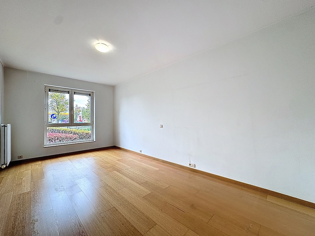 Salon moderne lumineux avec grande fenêtre, parquet en bois naturel, ambiance chaleureuse et épurée