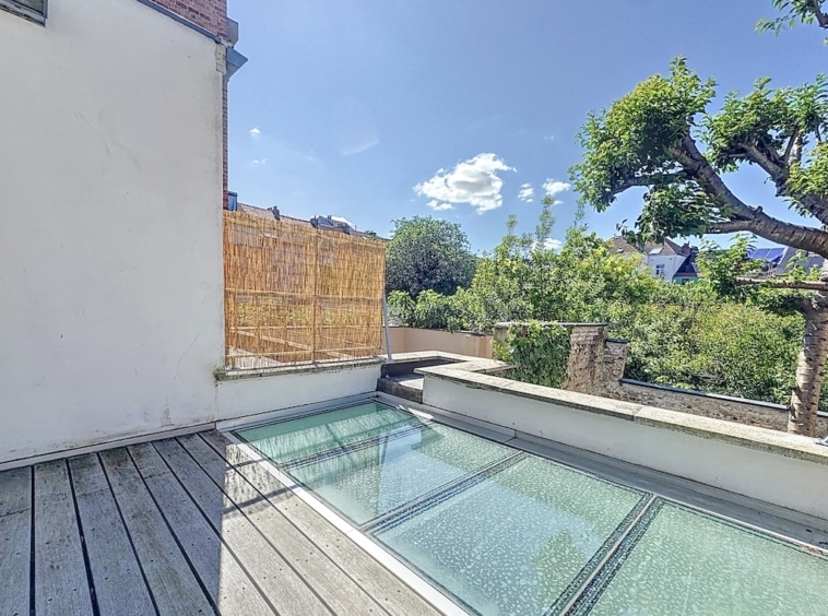 Terrasse en bois avec planchers en verre, vue sur la verdure et ambiance paisible.