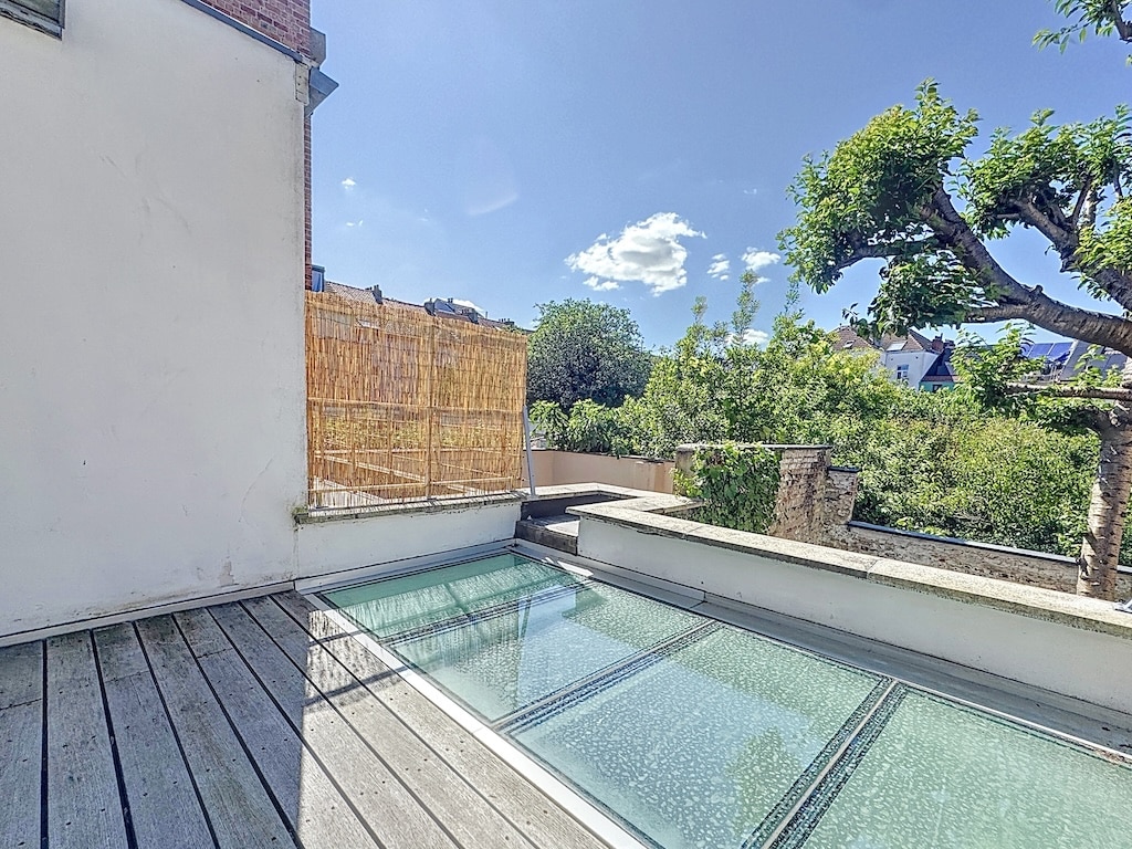 Terrasse en bois avec planchers en verre, vue sur la verdure et ambiance paisible.