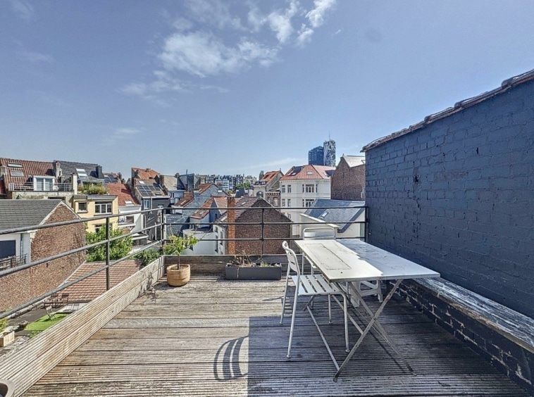 Terrasse urbaine avec vue panoramique, mobilier moderne, plantes en pot et ciel bleu.
