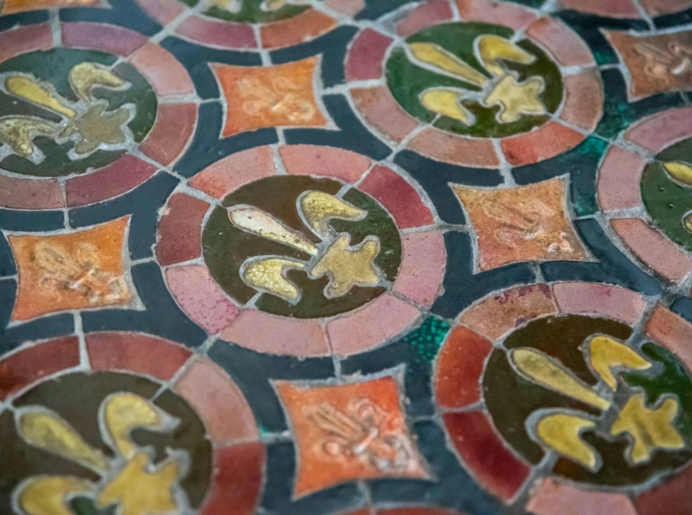 Carrelage ancien à motifs Fleur-de-Lis, couleurs vives, style historique et artisanat raffiné.