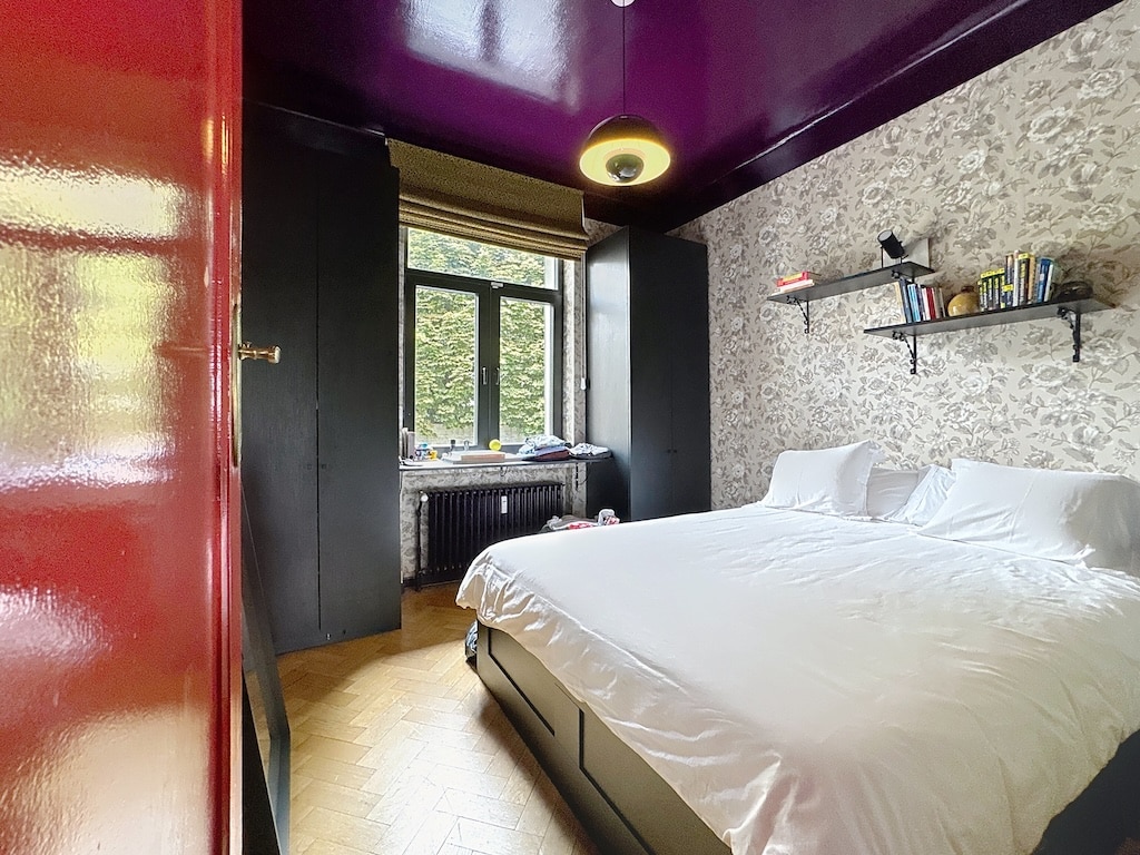 Chambre cosy moderne et vintage avec plafond violet, grande fenêtre et décoration élégante.