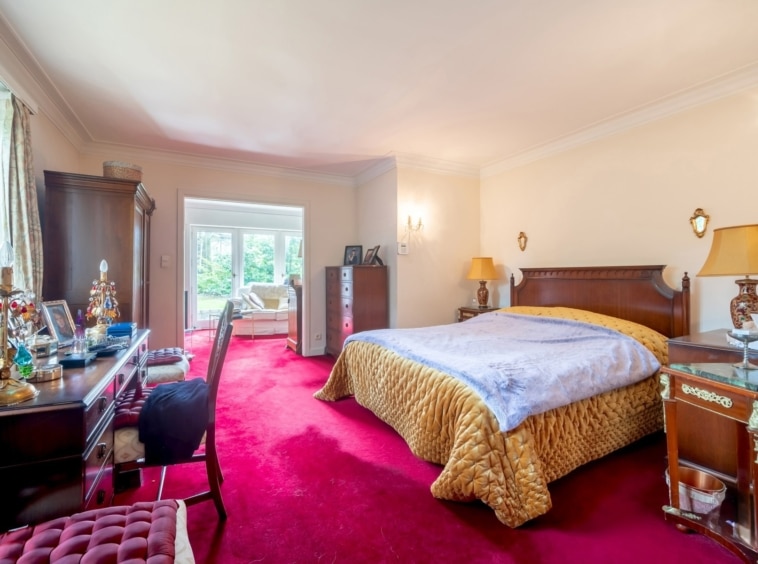 Chambre élégante avec lit, bureau, éclairage doux et coin salon, alliant confort et style classique.