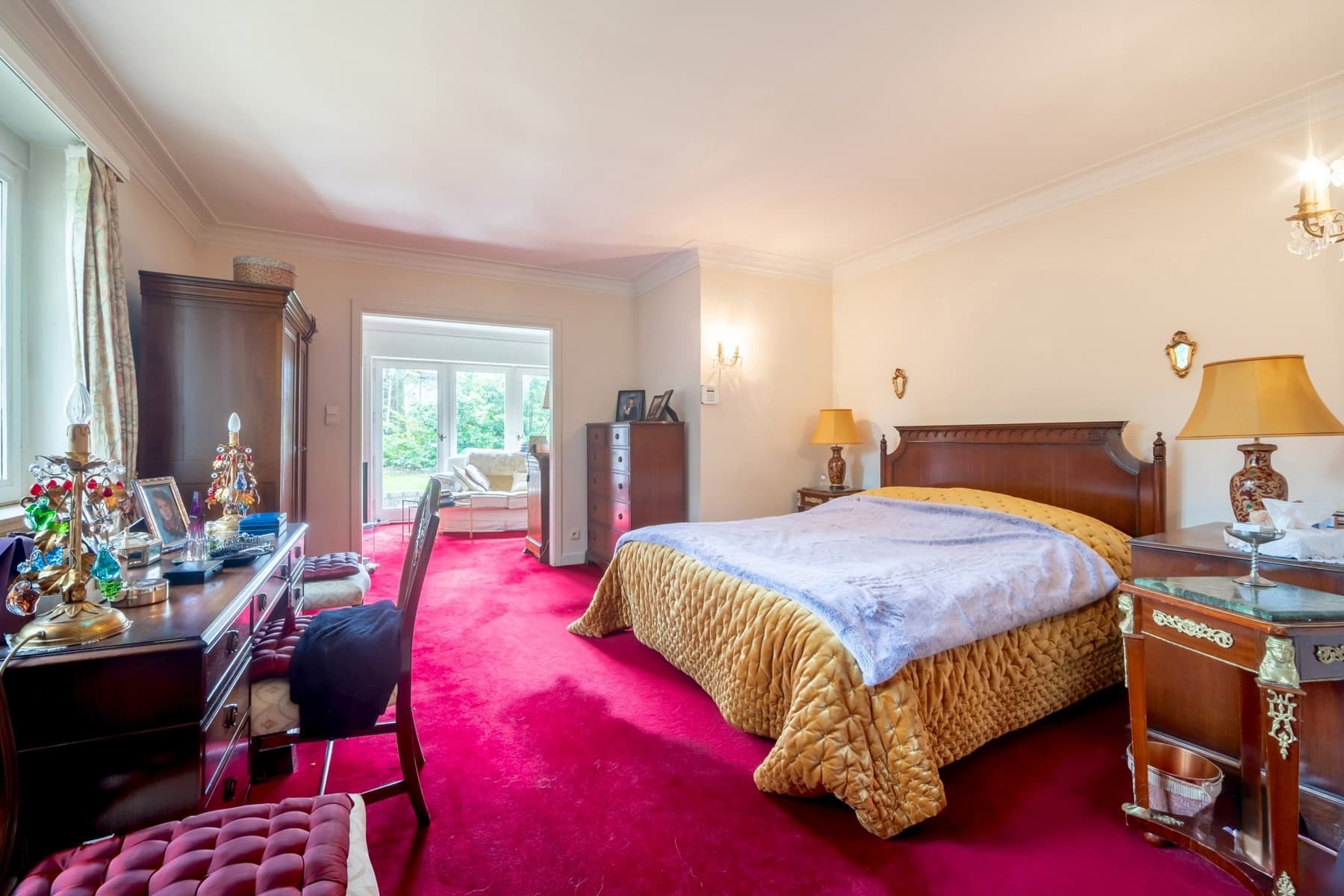 Chambre élégante avec lit, bureau, éclairage doux et coin salon, alliant confort et style classique.