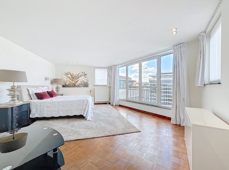Chambre moderne lumineuse avec fenêtres panoramiques, lit élégants, lumière naturelle, ambiance cosy et raffinée.