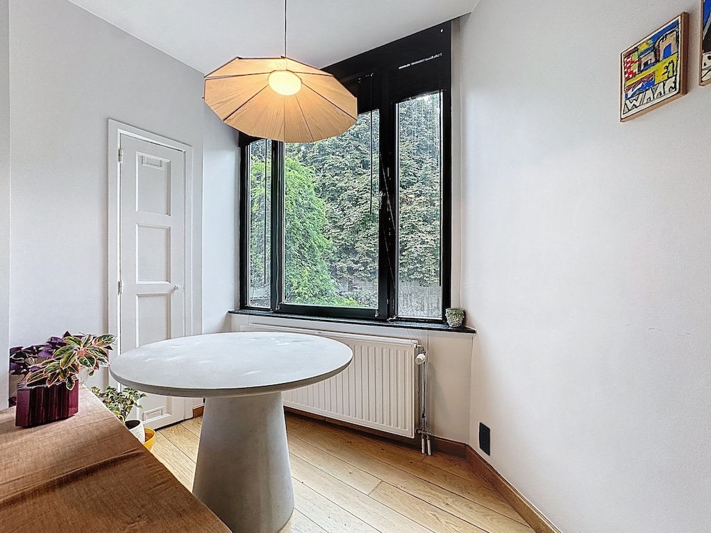 Coin détente minimaliste avec vue sur la nature, lumière chaleureuse et touche de verdure.