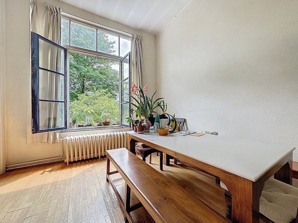 Coin repas lumineux avec vue nature, plantes vertes, bois chaleureux et ambiance cosy.
