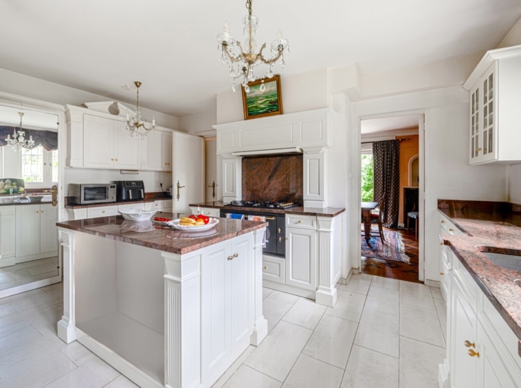 Cuisine lumineuse avec îlot central en granite, armoires blanches et éclairage naturel.