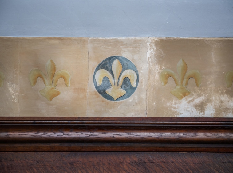 Décor mural élégant avec motifs de fleurs-de-lis dorées, cercle bleu et bande en bois sombre.