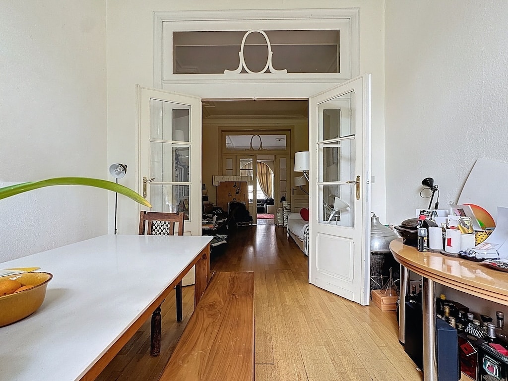 Entrée lumineuse avec porte double en verre, espace de vie moderne et coin de travail chaleureux.