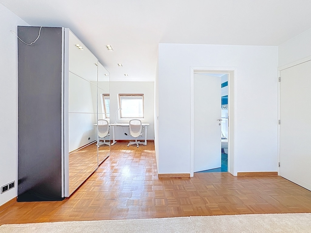 Espace moderne et lumineux avec miroir, bureau épuré, murs blancs et sol en bois chaleureux.