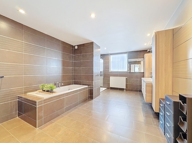 Salle de bain moderne, lumineuse, spacieuse avec baignoire, douche en verre et décor nature.