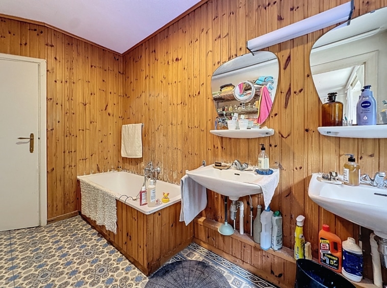 Salle de bain rustique avec baignoire, miroirs ronds, bois chaleureux et décoration élégante.