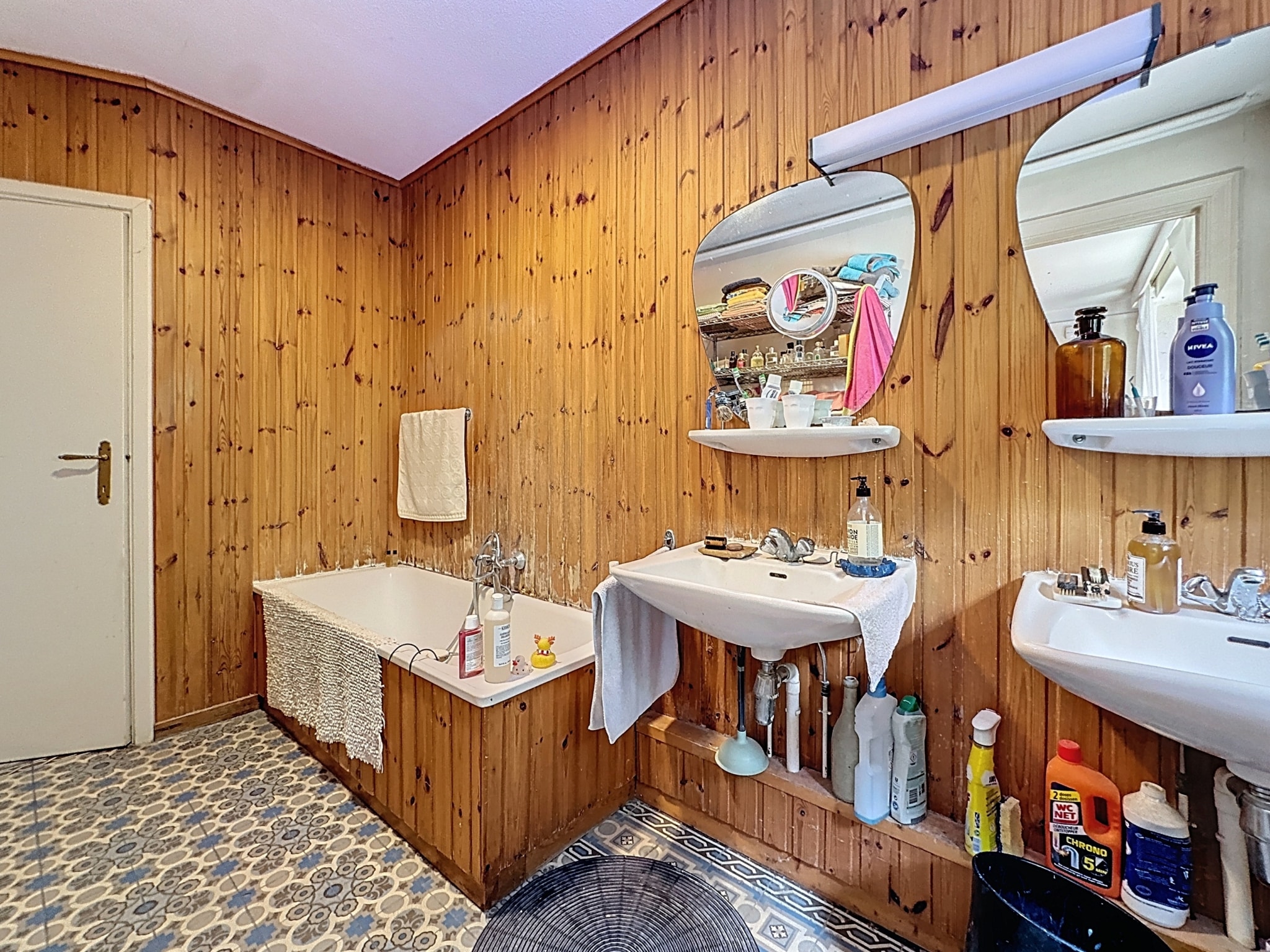 Salle de bain rustique avec baignoire, miroirs ronds, bois chaleureux et décoration élégante.