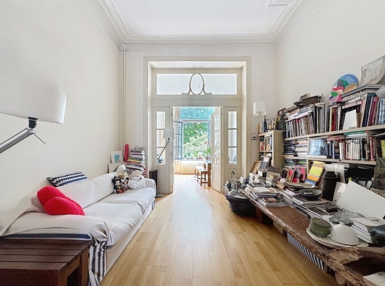 Salon cosy avec bibliothèque, espace de travail, vue extérieure et lumière naturelle.