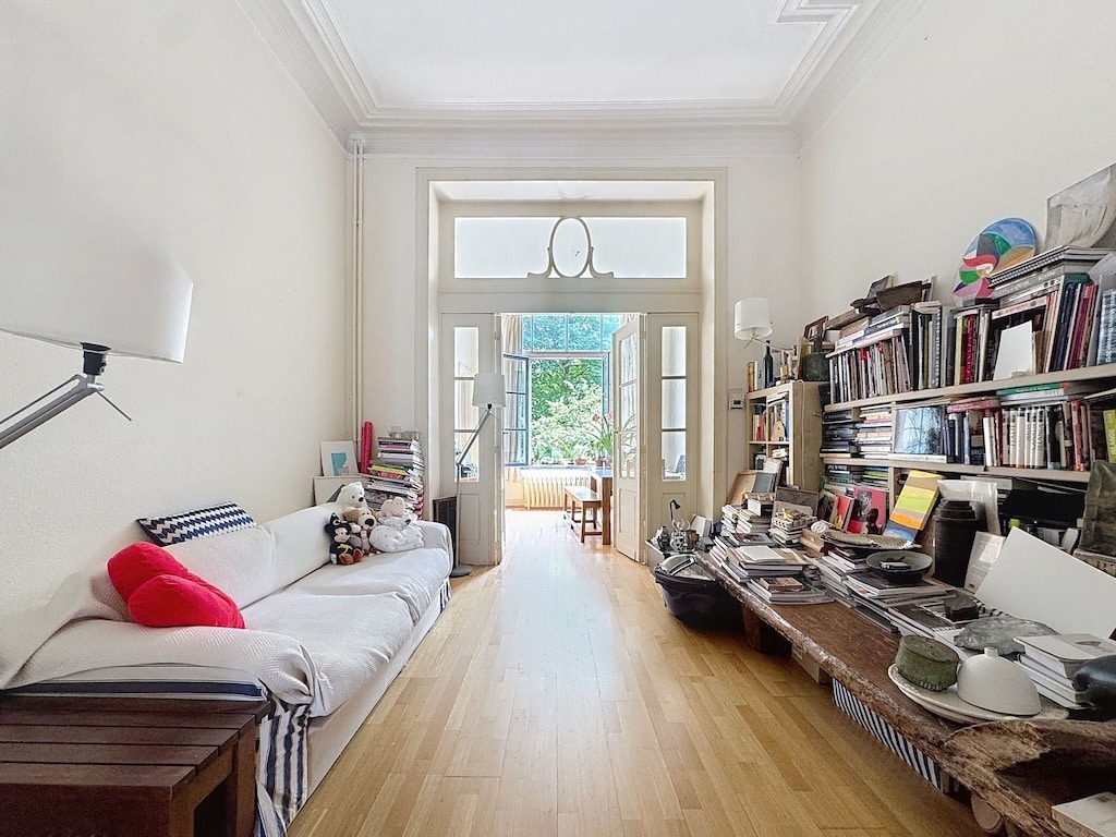 Salon cosy avec bibliothèque, espace de travail, vue extérieure et lumière naturelle.