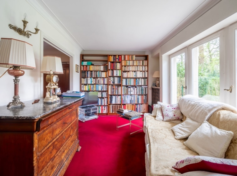 Salon chaleureux avec bibliothèque, canapé beige et éclairage doux, idéal pour la détente et la lecture.