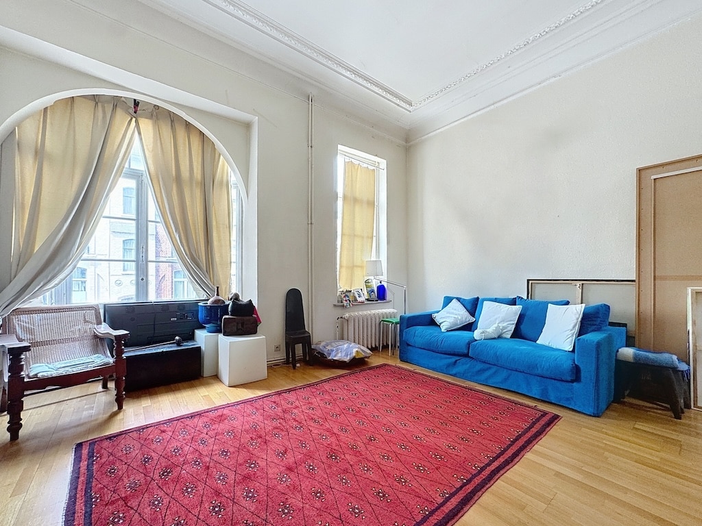 Salon lumineux avec canapé bleu, tapis rouge, mobilier élégant et ambiance chaleureuse.