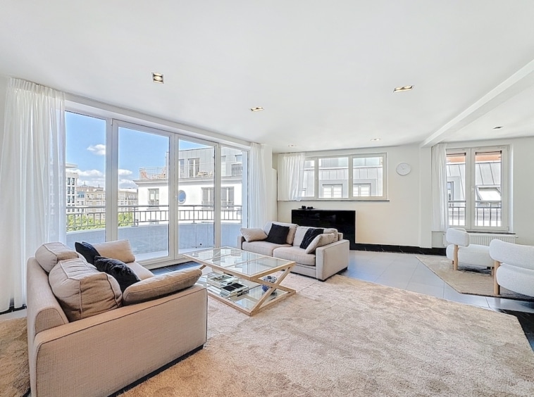 Salon moderne lumineux avec vue urbaine, canapé clair, cheminée élégante, ambiance chic et chaleureuse.