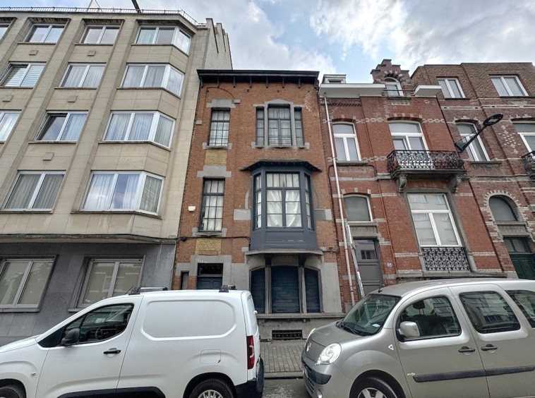 Ville colorée avec bâtiments modernes en verre et anciennes maisons en brique sous ciel nuageux.