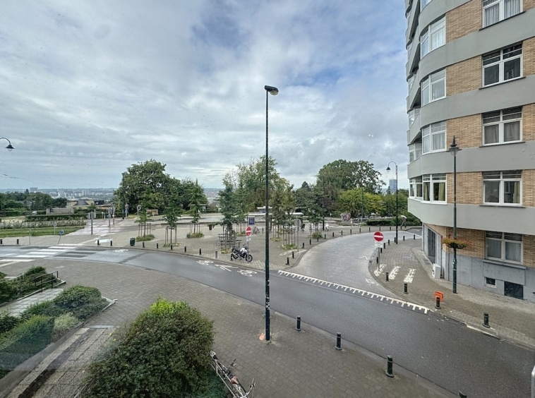 Rond-point moderne avec verdure, bâtiments contemporains et ciel nuageux apaisant.