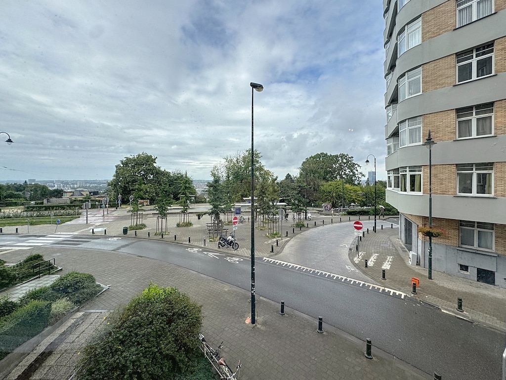 Rond-point moderne avec verdure, bâtiments contemporains et ciel nuageux apaisant.