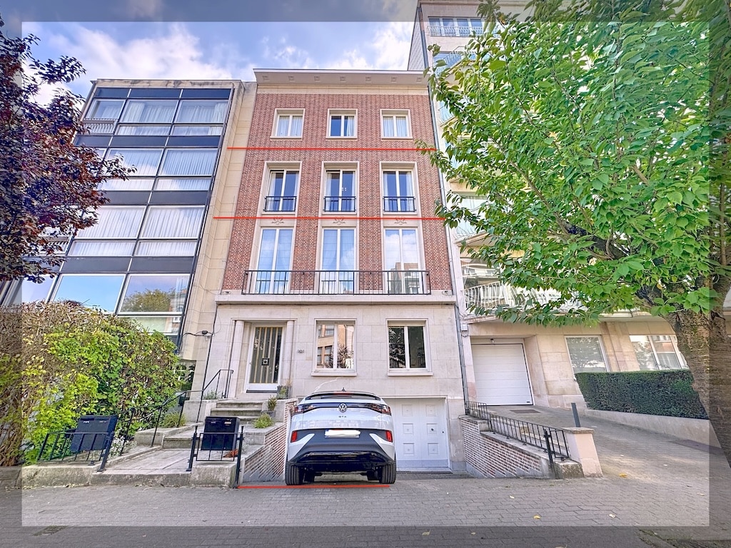 Façade moderne en briques et verre avec parking souterrain et jardin urbain élégant.