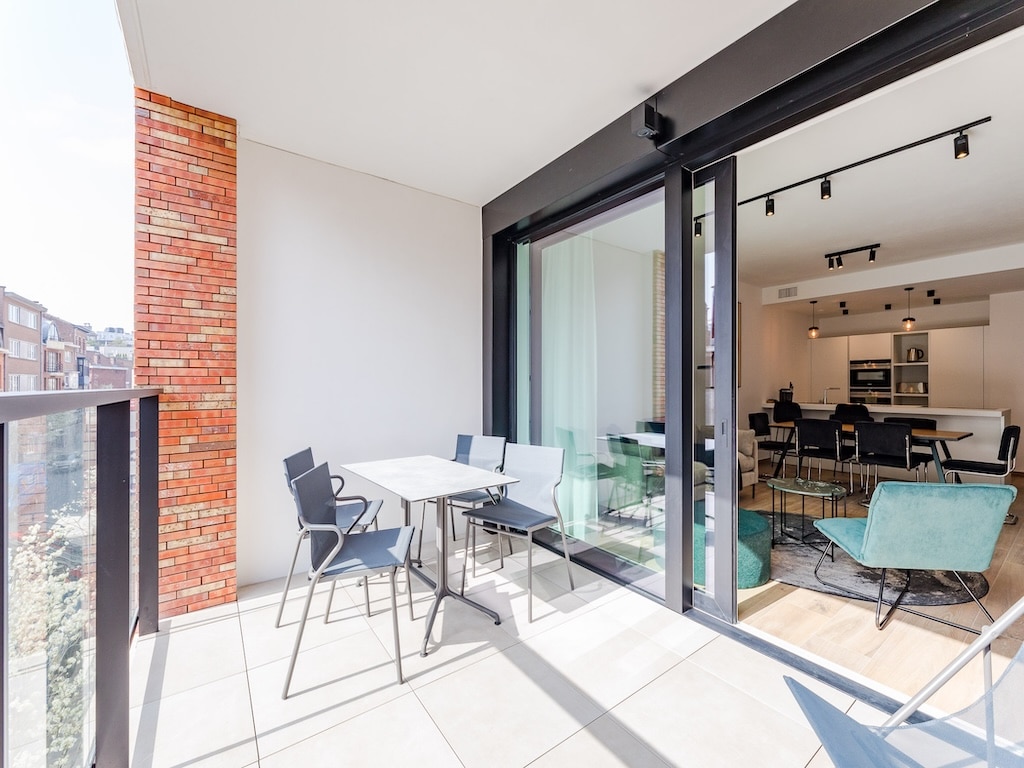 Balcon moderne avec mobilier design, mur en briques rouges et vue urbaine lumineuse.