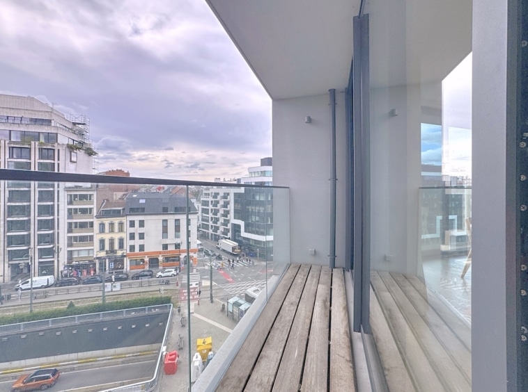Balcon moderne avec vue urbaine sur ville animée, design épuré, bois et verre.