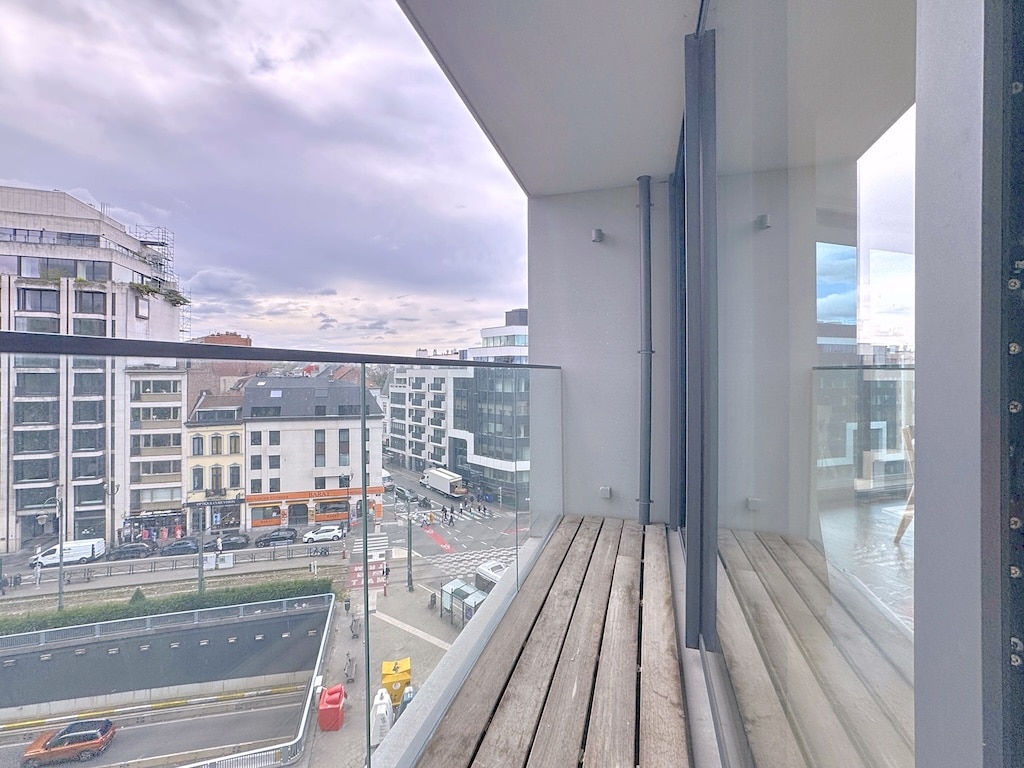 Balcon moderne avec vue urbaine sur ville animée, design épuré, bois et verre.