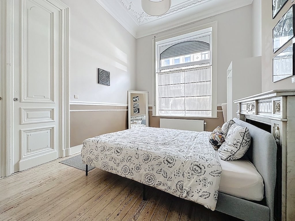 Chambre lumineuse et élégante avec lit floral, miroir, mobilier minimaliste et ambiance zen.