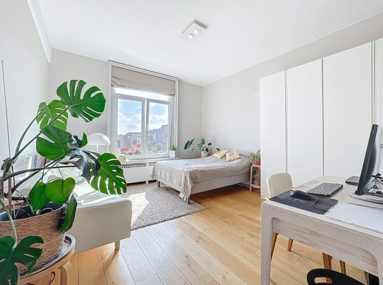 Chambre minimaliste lumineuse avec mobilier en bois, plante verte et ambiance zen et apaisante.