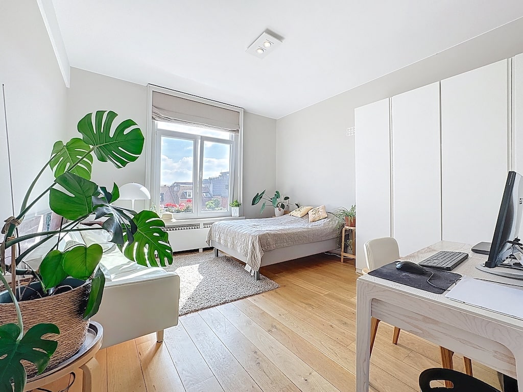 Chambre minimaliste lumineuse avec mobilier en bois, plante verte et ambiance zen et apaisante.