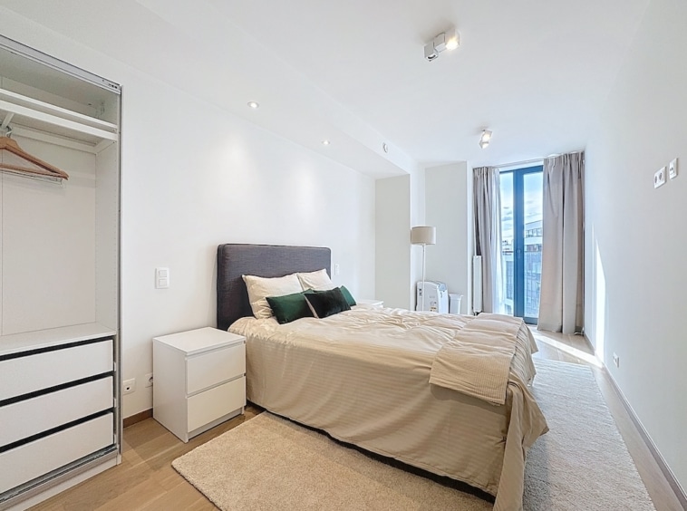 Chambre moderne minimaliste avec luminosité naturelle, lit neutre, rangement miroir et ambiance sereine.