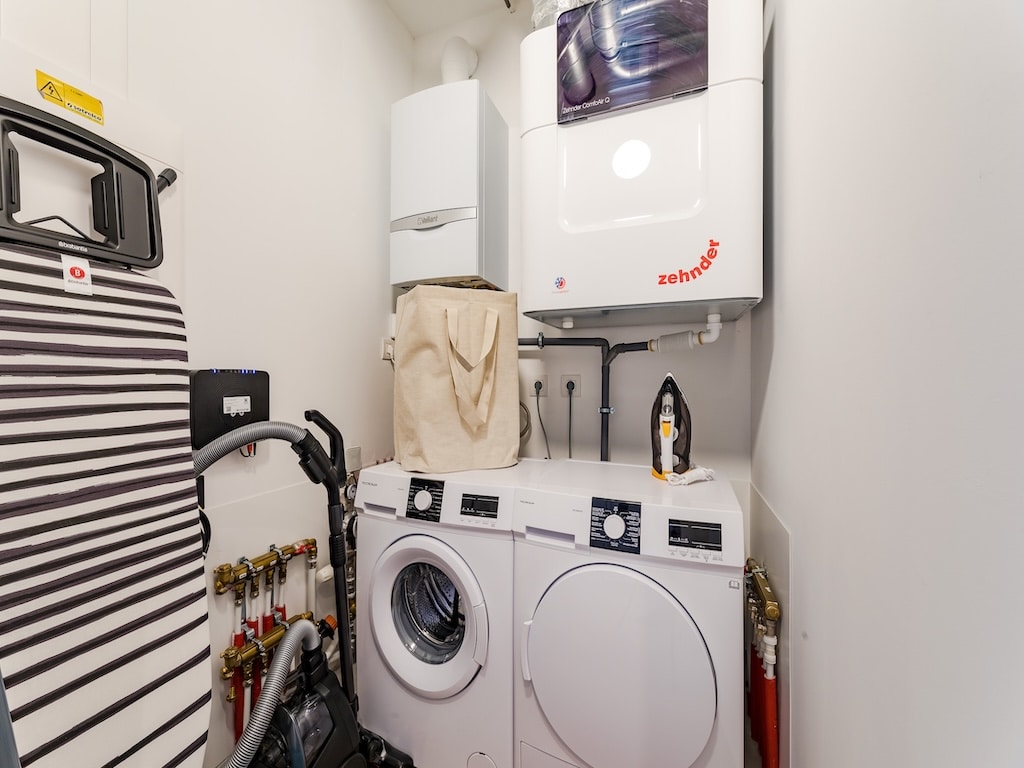 Coin buanderie compacte, lave-linge empilé, sèche-linge, planche à repasser à rayures, espace organisé.