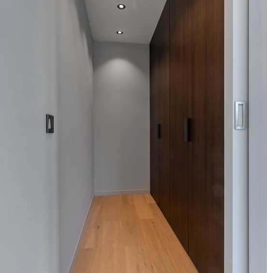 Couloir moderne en bois clair, panneau en bois foncé, éclairage doux, ambiance calme et élégante.
