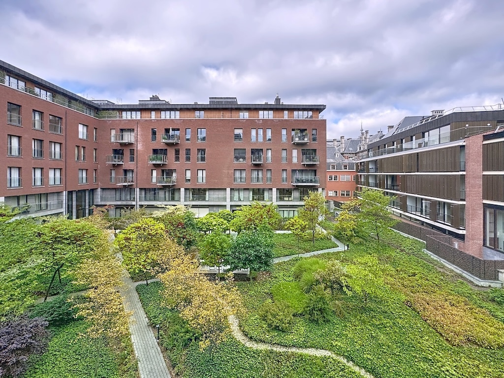 Courtyard urbain moderne avec verdure, architecture contemporaine et espace paisible en milieu urbain.