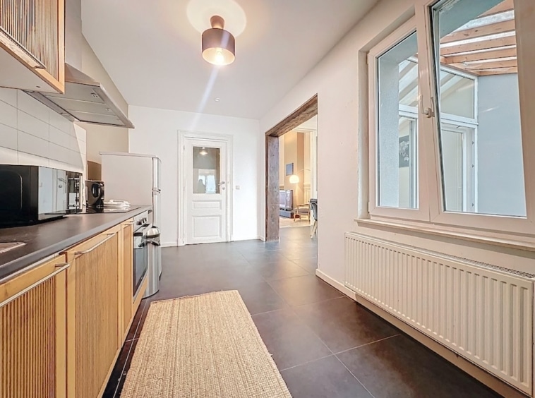 Cuisine moderne, lumineuse, chaleureuse avec plans en acier, meubles en bois et espace convivial.