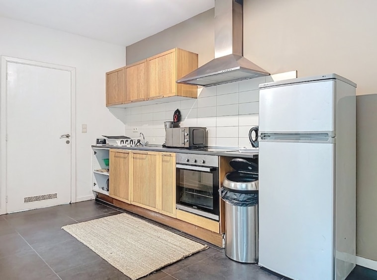 Cuisine moderne et lumineuse avec mobilier en bois clair, électroménagers inox et sol foncé élégant.