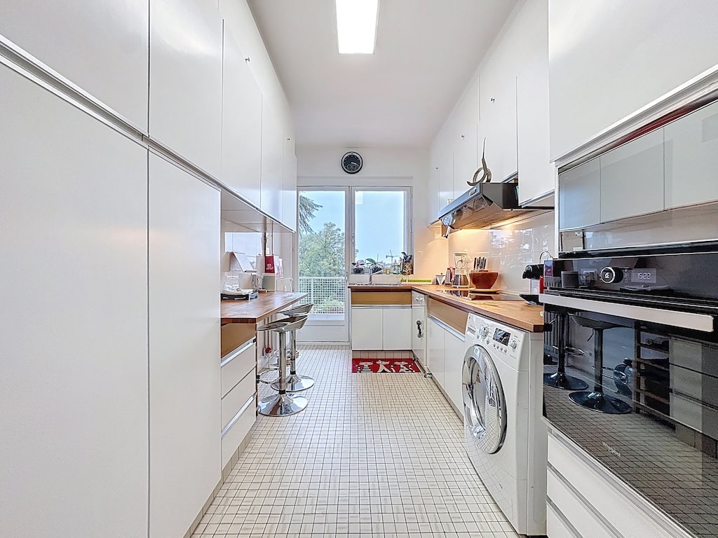 Cuisine moderne lumineuse, rangements intégrés, coin petit-déjeuner, appareils haut de gamme, vue extérieure.