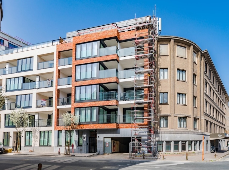Construction moderne urbaine avec balcons en verre, mêlant design contemporain et architecture traditionnelle.