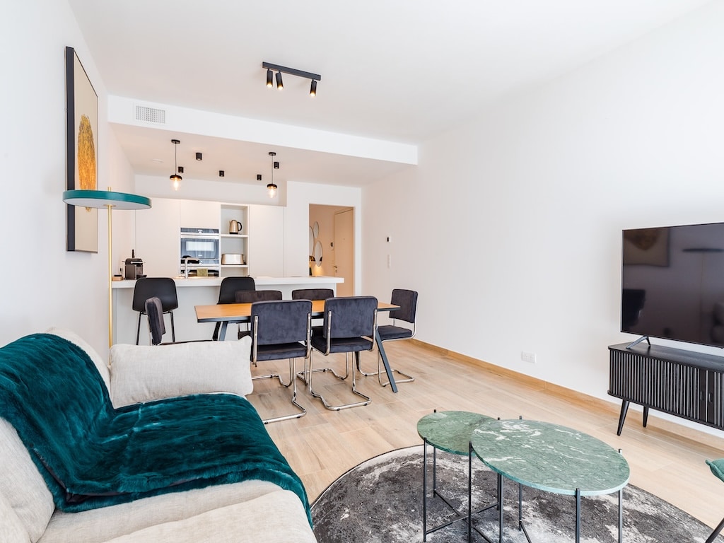 Salon moderne minimaliste avec canapé beige, mobilier épuré, espace dining élégant et lumière chaleureuse.