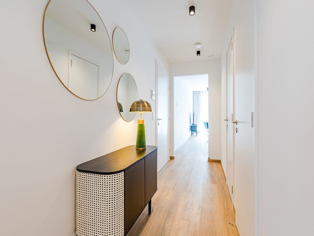 Hallway contemporain avec miroirs ronds dorés, console élégante et décoration minimaliste.
